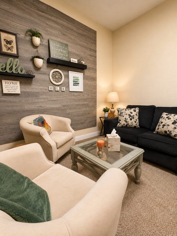 Inviting therapy room with cream armchairs, a wood accent wall, and a welcoming 'hello' sign at Living Well Counseling & Consulting