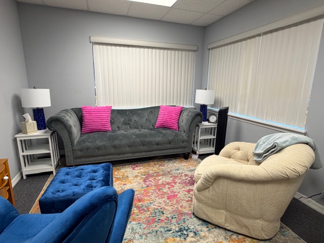 Elegant therapy room with tufted grey sofa and vibrant area rug