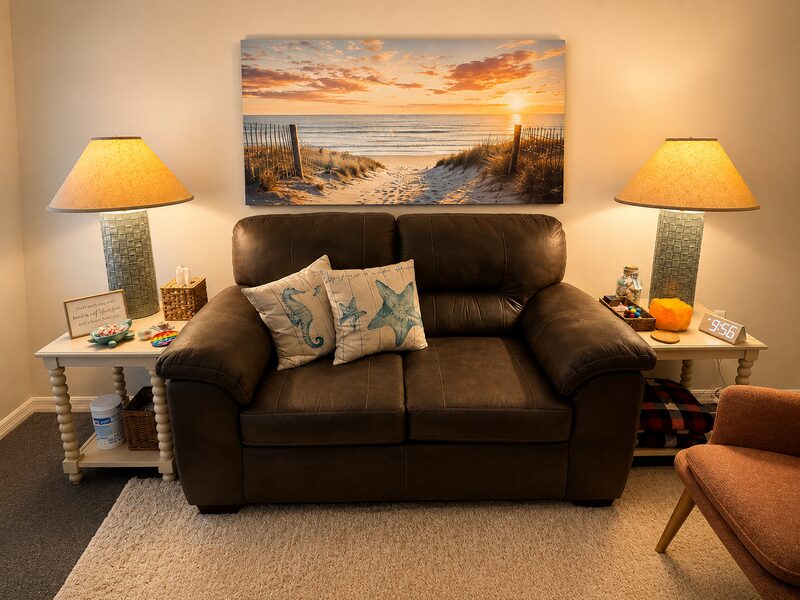 Cozy room with a brown leather loveseat beneath a sunset beach canvas and matching table lamps